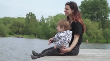 Oğlan ve anne tahta iskelede oturuyor.