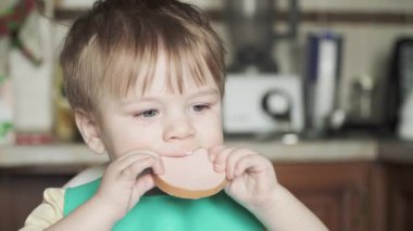 Çocuk pişmiş sosis yiyor.