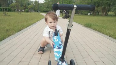 Çocuk scooter sürmeyi öğreniyor.