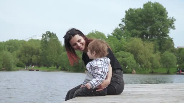 Ragazzo con mamma seduto su un molo di legno — Video Stock