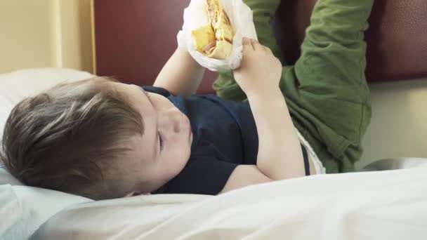 Pojken äter shawarma på hyllan till bilen. — Stockvideo