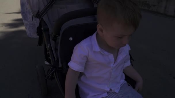 Seorang anak laki-laki di kereta bayi di langkah — Stok Video