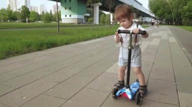 Çocuk scooter sürmeyi öğreniyor.