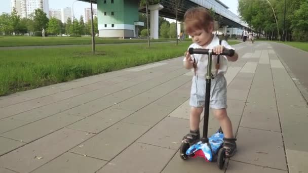 Jongen leert rijden op een scooter — Stockvideo