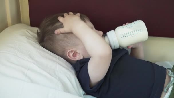 De jongen ligt op de plank van de auto en drinkt melk — Stockvideo