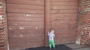 Tahta kapının yanında bir çocuk var.