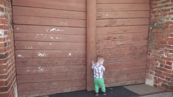 Un chico cerca de la puerta de madera — Vídeo de stock