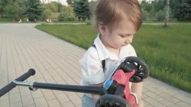 Bir çocuk omuzunda scooter taşıyor.