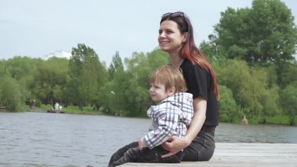 男の子とともにお母さん座っている木製の桟橋 — ストック動画