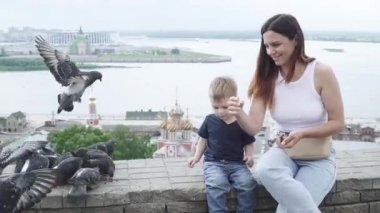 Anne oğluyla güvercin besliyor.