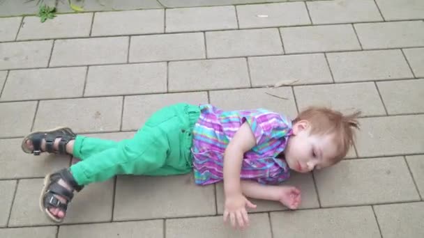 Мальчик лежит на бетонном полу — стоковое видео