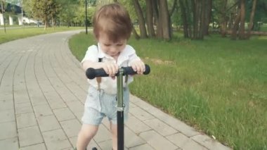 Çocuk scooter sürmeyi öğreniyor.