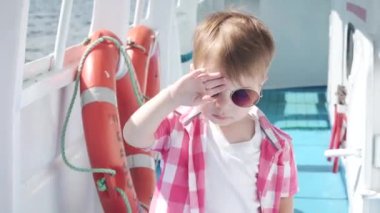 Gemide güneş gözlüklü çocuk var.