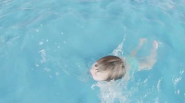 Çocuk havuza su sıçratıyor.