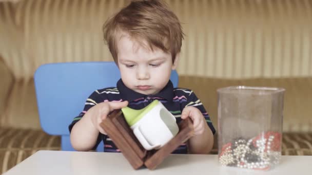 A kisfiút egy fadoboz játssza. — Stock videók