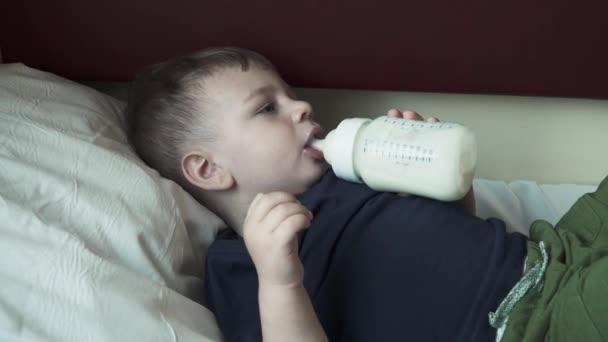 Le garçon se trouve sur l'étagère de la voiture et boit du lait — Video