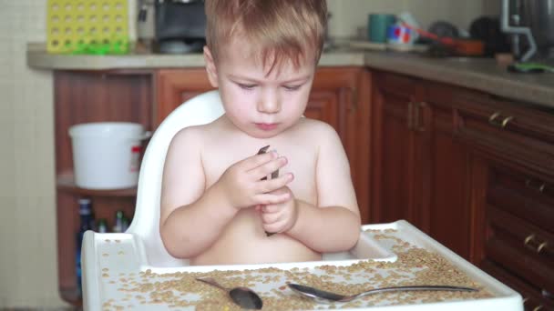 Мальчик играет с горохом и бобами — стоковое видео