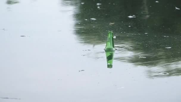 Зеленая стеклянная бутылка, плавающая в воде — стоковое видео
