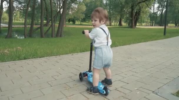 Chico aprende a montar un scooter — Vídeo de stock