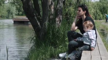 Oğlan ve anne tahta iskelede oturuyor.