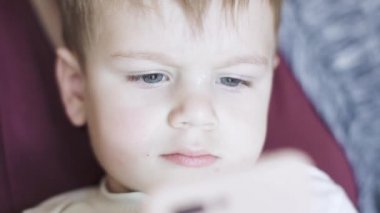 Çocuk annesinin kollarında oturuyor.