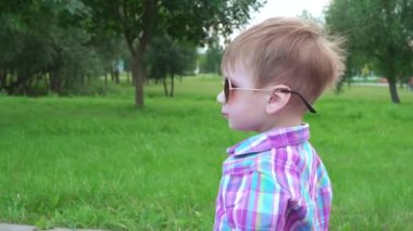 Güneş gözlüklü çocuk yürüyor.