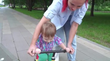 Anne oğluna ata binmeyi öğretiyor.