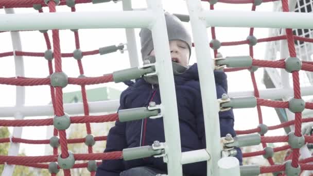 Um menino caminha em um playground — Vídeo de Stock