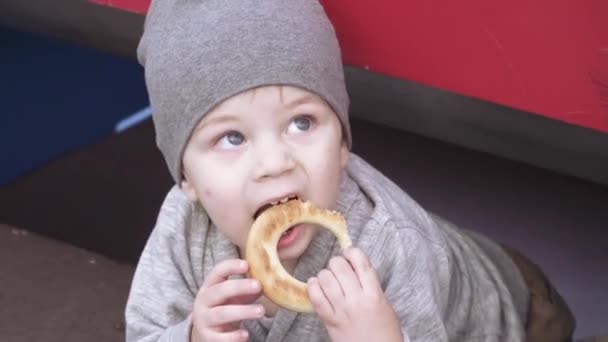 Dreng med en bagel i parken – Stock-video