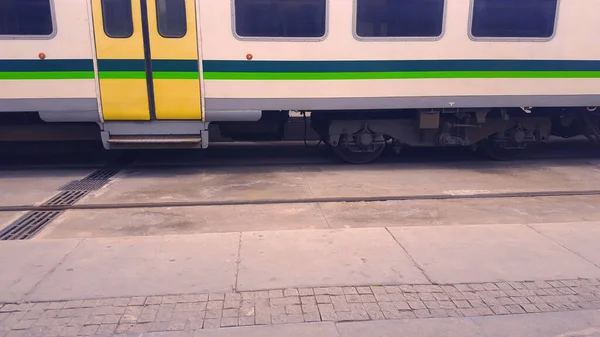 Yolcu vagonunu durdurdu, tren istasyonunda, tren istasyonunda, tren istasyonunda ya da depoda kamyonlar durdu. Renkli yeşil ve sarı çizgileri olan beyaz tren.