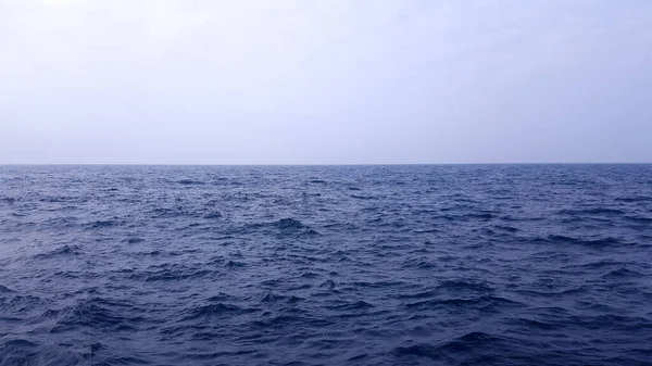Açık mavi okyanus suyu beyaz gökyüzüne karşı. Güzel deniz manzarası.