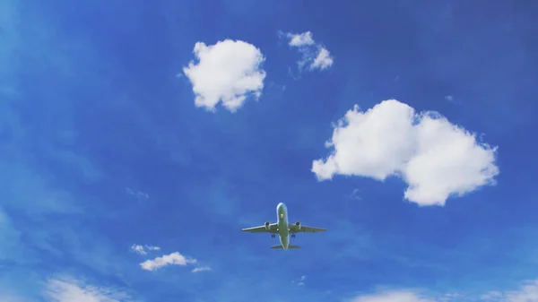 Mavi gökyüzünde bulutlu bir uçak. Uçan uçağın altından görünüyor. Düşük açılı çekim arkaplanı kopyalama alanı.