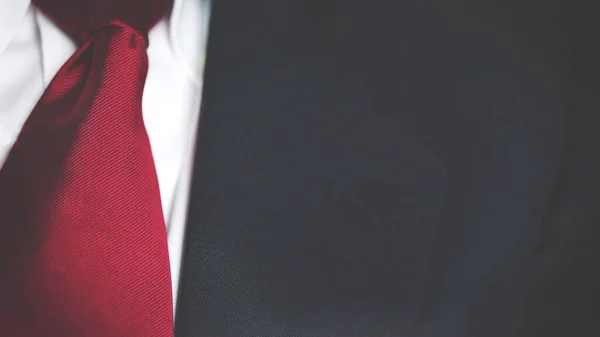 Beyaz gömlekli, kırmızı kravatlı siyah bir iş ceketi, erkek göğsü. Fotokopi alanı olan dokuyu kapat..