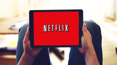 New York, ABD - 28 Şubat 2019: Tablet ekrandaki Netflix uygulama logosu, evde diziyi izleyen bir kişi.