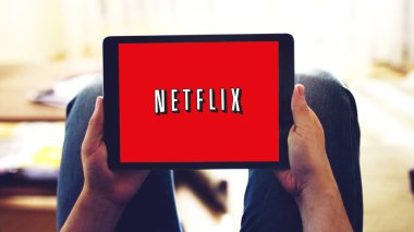 New York, ABD - 28 Şubat 2019: Tablet ekrandaki Netflix uygulama logosu, evde diziyi izleyen bir kişi.