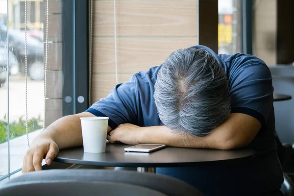 Kahve dükkanında oturan sinirli orta yaşlı adam.