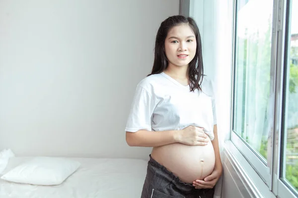 Mulher grávida tailandesa feliz com grande barriga relaxar em casa. Retrato — Fotografia de Stock