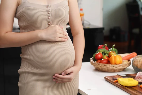 Femme enceinte en robe tient la main sur le ventre sur un backgrou blanc — Photo