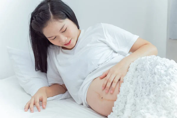 La mujer embarazada está acariciando y mirando su estómago . — Foto de Stock