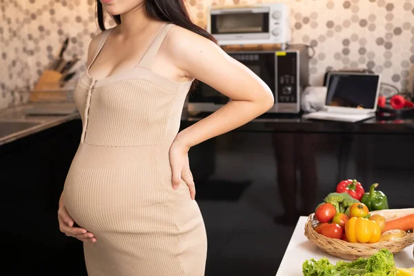 Femme enceinte en robe tient la main sur le ventre sur un backgrou blanc — Photo