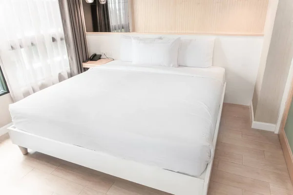 Beyaz ikiz yatak ahşap ve pastel süslemeli bir odada..