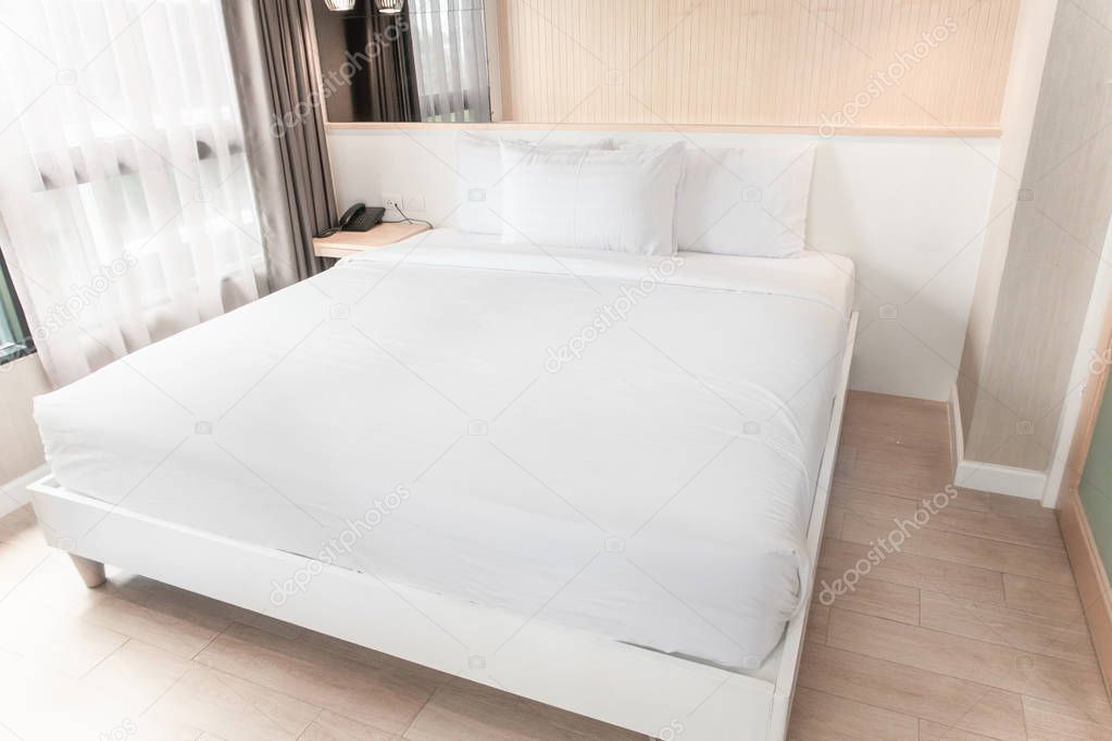 The white twin bed is set in a wood and pastel decorated room.