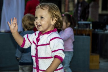 bir gülümseme ile bir çocuk elini sallayarak selamlıyor