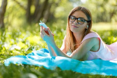 Kızı yere bırak veya yeşil rahatlatıcı müzik dinleme smartphone ile yaz veya bahar çimen