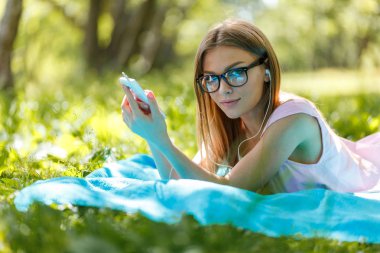 Kızı yere bırak veya yeşil rahatlatıcı müzik dinleme smartphone ile yaz veya bahar çimen