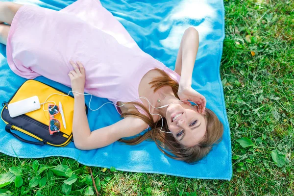 Kadın rahatlatıcı müzik cep telefonunda bir parkta çim