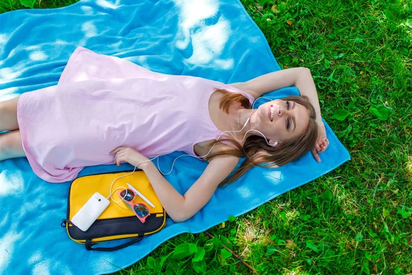 Kadın rahatlatıcı müzik cep telefonunda bir parkta çim