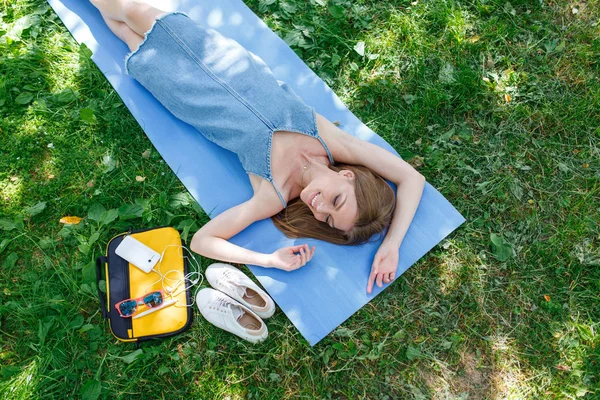 Güzel kadın bir parkta çim üzerinde rahatlatıcı. Üstten görünüm