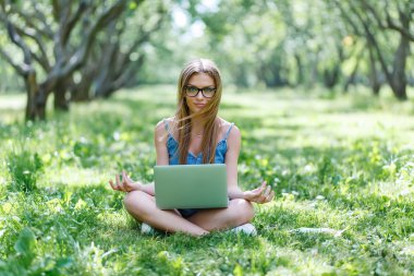 Lotus pozisyonda onu laptop ile parkta oturan öğrenci