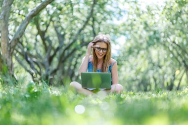 Lotus pozisyonda onu laptop ile parkta oturan öğrenci